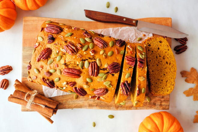 Fall pumpkin bread sliced. Overhead view table scene on a white marble background.