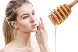 Young woman and honey spoon prepare for facial mask. Honey treatment concept.