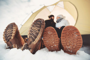 close up sole winter shoes. young couple sitting in tent in the snow and celebrating during winter vacation, summertime and holidays concepts.