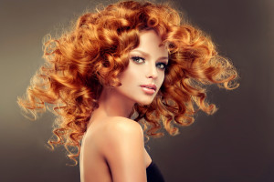 Girl model with long red wavy hair. Big curls on the red head . Hairstyle permanent waving