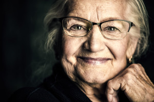 Portrait of a beautiful senior woman in elegant glasses smiling at camera.