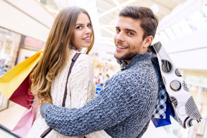 Happy young couple shopping and holding bags.Image taken inside a shopping mall.