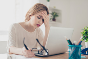 Overworked businesswoman suffering from headache and thinking how to end work