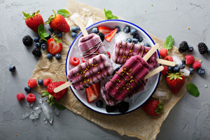 Mixed berry ice cream popsicles with chocolate glaze on a plate