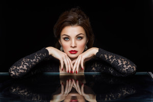 beautiful young woman with red lips and fancy hairstyle wearing black dress. studio beauty shot on black background. copy space.