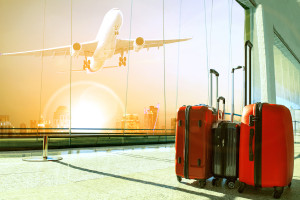 stack of traveling luggage in airport terminal building and passenger plane flying over urban scene