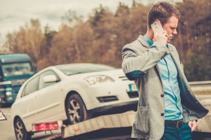 Man calling while tow truck picking up his broken car