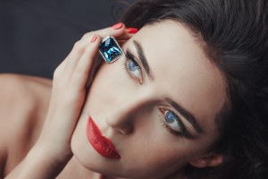 Chic style. Close-up portrait of sensuality beautiful woman model face with fashion make-up, sexy evening red lips makeup and bright red manicure, red lipstick, blue eyes, blue sapphire jewelry ring