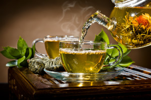horizontal photo of the glass teapot flow green tea in cup on brown background tea ceremony