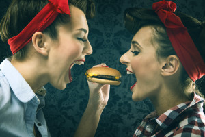 Vintage girlfriends in old style dress eat hamburgers