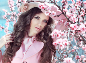 Beautiful brunette girl posing over Pink Spring Cherry blossoms. Enjoyment. Beauty girl.