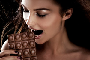 Portrait of attractive young woman with chocolate. Brunette girl . Studio shot.