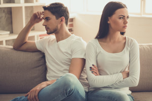 Beautiful young couple is having a quarrel while sitting on sofa at home