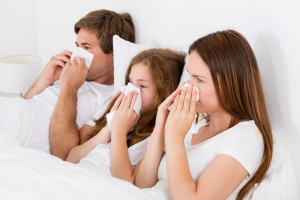 Family Lying On Bed Blowing Their Nose