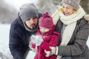 Young happy family playing with snow together outdoors on a beautiful winter day