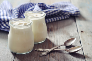 Greek yogurt in a glass jars with spoons on wooden background