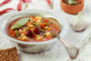 Eintopf - German traditional thick soup with meat and vegetables - potatoes, carrots, onions, red and green beans, corn and tomatoes with seasonings and spices. Rustic style. Selective focus