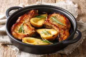 Hot spicy baked pork chops with pears and rosemary in honey-garlic sauce served in a pan close-up on the table. horizontal