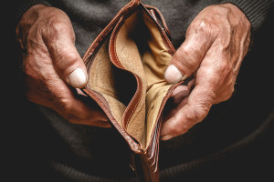 Empty wallet in the hands of an elderly man. Poverty in retirement concept