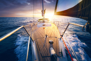 Sunset at the Sailboat deck while cruising / sailing at opened sea. Yacht with full sails up at the end of windy day. Sailing theme - background.