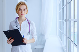 Portrait of serious female doctor with clipboard