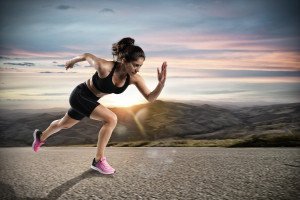 Athletic woman runs on the street during sunset