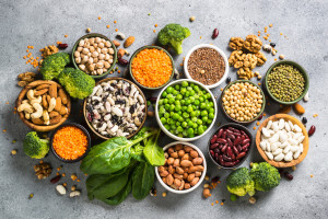 Vegan protein source. Legumes, beans, lentils, nuts, broccoli, spinach and seeds. Top view on stone table. Healthy vegetarian food.