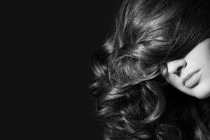 Black and white close-up shot of woman with long curly hair, selective focus