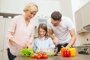 food, family, hapiness and people concept - happy family making dinner in kitchen