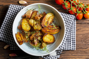 Appetizing stew of pork tenderloin meat cooked in the wok, cut into cubes. With roasted and golden potatoes, garlic, salt, oregano and fresh tomatoes. Homemade look. Top view.