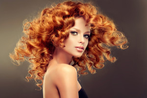 Girl model with long red wavy hair. Big curls on the red head . Hairstyle permanent waving