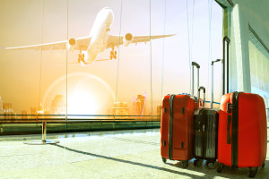 stack of traveling luggage in airport terminal building and passenger plane flying over urban scene