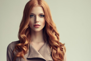 Red head  girl with long  and   shiny wavy hair .  Beautiful  model woman with curly hairstyle .