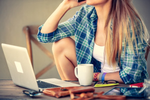 Beautiful student girl working at home on laptop, doing homework with help of wireless intenret, enjoying online communication, modern technology concept