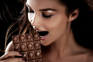 Portrait of attractive young woman with chocolate. Brunette girl . Studio shot.