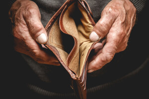 Empty wallet in the hands of an elderly man. Poverty in retirement concept