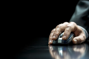 Closeup of the hand of a businessman using a wireless mouse to communicate with his computer and navigate the internet
