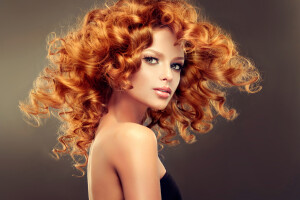 Girl model with long red wavy hair. Big curls on the red head . Hairstyle permanent waving