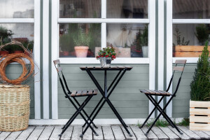 Winter terrace with wicker baskets and green plants in pots on porch home. Wooden table and chairs on veranda of house. there is potted Christmas mistletoe on table in street cafe. Outdoor home decor