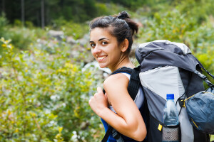 Smiling woman going to a trip in the forest.