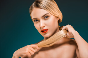 portrait of beautiful young woman with red lips holding hair on dark background