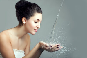 Woman and water splash. Water drops and bubbles in girls hands. Woman with young beauty face and water